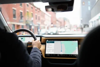 : Interiér elektromobilu Rivian s veľkým centrálnym displejom zobrazujúcim navigáciu počas jazdy v meste.