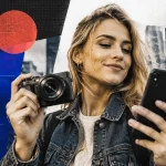 Dievča drží kompaktný fotoaparát vedľa smartfónu v modernej mestskej scéne s jemnými digitálnymi prvkami vizuálnej identity.