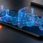 Smartfón na pracovnom stole so zobrazenou mapou USA a jemnými digitálnymi bariérami znázorňujúcimi distribúciu a mobilných operátorov.